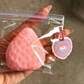 Detailed view of the large pink strawberry squishy toy held in hand within clear packaging - Pink Strawberry Squishy / Pink