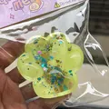 Detail view of a yellow glittery starry cat paw squeeze toy in clear plastic wrap - Galaxy Yellow Cat Paw