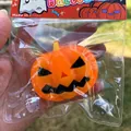 Close-up of vibrant orange Halloween pumpkin squishy toy in clear plastic bag - Pumpkin / Orange