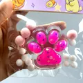 Primo piano di uno squishy a forma di zampa di gatto rosa con pompon decorativi colorati - Zampa di Gatto in Cristallo Rosso Rosa / Rosso rosa