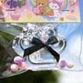 Detail view of a clear paw-shaped squishy toy with glitter and a black bow in cute packaging. - Transparent Crystal Cat Paw / Clear