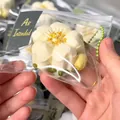 Detailed white flower-shaped squishy stress relief toy in a clear blind bag package - Beige Osmanthus Cake