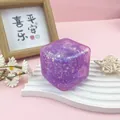 Vista detallada de un juguete antiestrés con forma de cubito de hielo morado brillante - Púrpura estrellado