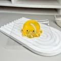 Nahaufnahme eines gelben Oktopus-Stressspielzeugs auf einem weißen wellenförmigen Tablett - Gelb