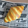Realistic slow rebound PU croissant squeeze toy presented on decorative paper background - Croissant Style