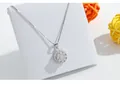 Primer plano de un collar con colgante de plata brillante en un soporte blanco. - Collar Giratorio / Oro blanco