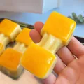 Handheld yellow simulation food squishy toy being stretched for sensory stress relief - Stretchy Rice Cake Style