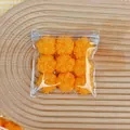 Close-up view of nine orange fuzzy coconut milk squishy toys in a clear plastic bag - Nine Cat Claws (Fried) / 9 Pieces Set