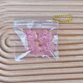 Detail of four pink cat paw squishies in a transparent zip bag with a yellow chain - Set of 4 / Pink
