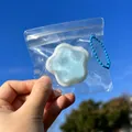 Handheld close-up of a blue star-shaped squishy toy in a clear bag with a chain - Star Squishy / Blue