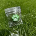 Green and white cat paw squishy toy in clear packaging bag with purple chain - Green Base White Paw