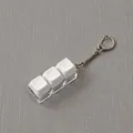Detail of mechanical keyboard keycap keychain with three white keys and clear base. - 3 Keys