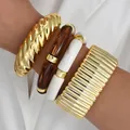 Chunky gold and acrylic bangle set worn on a model's wrist with elegant white background - Twisted Ripple Bangle (6685801HB) / Four-Piece Set / Gold Amber Milky White Combo