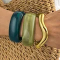 Set of chunky acrylic bangles with wavy gold bracelet on a woven straw background - 3-Piece Irregular Wave Bangle Set (6778201HB) / Gold, Deep Teal and Olive Green