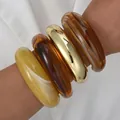 Elegant acrylic irregular bangle set featuring amber and gold finishes shown on arm - Arc Open Style (6685501HB) / Set of 4 / Amber Gold Beige