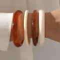Set of four acrylic bracelets in amber and marbled cream for a minimalist high-end look - Cylindrical Bangle (6532801) / Set of 4 / Amber and Milky White Combo