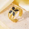 Dettaglio ravvicinato di un anello aperto in acciaio inossidabile dorato con fiore - Taglia unica / Stile Fiore a Quattro Petali Nero (A522)