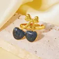 Détail de la bague cerise dorée avec pierres en cœur sur un présentoir en pierre - Taille unique / Style Forme Cerise Noire (A522)