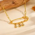 Macro detail view of gold safety pin necklace with three hanging crystals on wood backdrop. - Safety Pin White Rhinestone Style (A616)