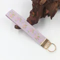 Nahaufnahme eines lavendelfarbenen Schlüsselanhängers mit Blumenstickerei und Goldring. - Lila Rosa Floral (04-14C)