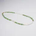 Gros plan de pierres vertes irrégulières et de perles d'eau douce blanches sur un collier - Ras du cou en pierres concassées bleu-vert et perles d'eau douce