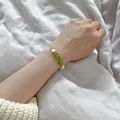 Détail d'un bracelet perlé fait main en pierre verte concassée et perles d'eau douce au poignet - Bracelet en pierres concassées vert olive et perles d'eau douce