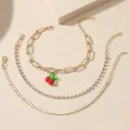 Dettaglio di un set di quattro cavigliere dorate con ciondolo a ciliegia e strass - Bracciale Ciliegia con Catena a Graffetta Oro (wg-0780)
