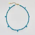 Detailaufnahme einer blauen Vintage-Türkis-Halskette mit goldenem Herzanhänger im Design - Frische blaue Halskette mit Röhrenperlen und Blattanhänger