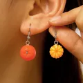 Close-up of realistic 3D resin orange fruit earrings with textured peel and vibrant color - Orange Asymmetric Style