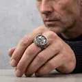Detailed macro shot of vintage stainless steel ring with ship and octopus design on finger - US 7 / Steel