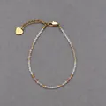 Macro detail van deze Boheemse natuursteen kralenarmband met een gouden hartbedeltje - Wit en oranje gefacetteerde kralenstijl (Armband 2) / 17+3cm