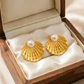 Detail of gold scallop shell earrings with pearl center in a wooden jewelry box. - Artificial Pearl Shell Style