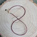 Détail d'un collier de perles en pierre naturelle rouge foncé sur fond de bois brut - 38+5cm / Violet foncé
