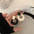 Pendientes de botón geométricos modernos en blanco y negro en la mano estilo joyero minimal - Pendientes geométricos en blanco y negro