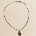 Vue détaillée d'un collier en argent avec pendentif œil de tigre sur un fond beige - Œil de tigre