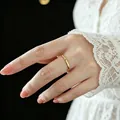 Detail of minimalist gold titanium steel ring with a sparkling small diamond on finger - US 4 / Gold