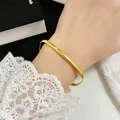Detailed view of a minimalist gold titanium steel bangle with a single inset crystal stone - One Size / Gold Color Bracelet