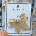 Élégante broche nœud en alliage doré avec perle et strass sur une carte-support - Style de Nœud (B243) / Or