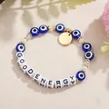 Detailansicht eines Evil-Eye-Armbands mit GOOD ENERGY Buchstabenperlen auf beigem Hintergrund. - GOOD ENERGY Stil (ZJ15923)