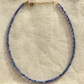 Close-up detail of blue natural stone beaded necklace with gold heart charm on linen - One Size / Blue Grey Mixed Style (Style 21)
