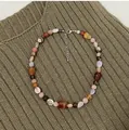 Close-up of vintage multi-color irregular natural stone necklace on textured knit fabric - One Size / Reddish Color Necklace
