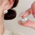 Detailed close-up of minimalist silver brushed metal round stud earrings worn by a model. - Silver 3D Brushed (ED2630-1)