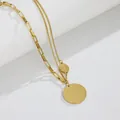 Close-up view of vintage double-layer gold necklace with engraved round disc pendants - Gold