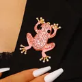 Detailansicht einer funkelnden rosa Frosch-Brosche mit Zirkonia auf schwarzem Sakko - Frosch / Rosa
