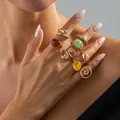 Set di anelli bohémien color oro con pietre colorate sulla mano di una modella - Set di Anelli con Pietre Preziose Retro (07253) / Oro