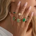 Elegante set di anelli boho dorati con pietre preziose verdi e crema sulle dita - Set di Anelli con Gemme Verdi (07231) / Oro