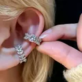 Elegant silver leaf cubic zirconia ear cuff set demonstrated on a female ear model. - Sparkly Leaf Ear Cuff Set (9589) / Two-Piece Set / Silver