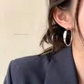 Detail of a minimalist silver hoop earring worn by a model in a stylish blazer. - Irregular Hoop Style (G210) / 30mm / Silver