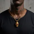 Detail view of a punk-style gold skull pendant with red eyes on a stainless steel chain. - Gold Rhinestone Pendant + Gold 3.0 Box Chain