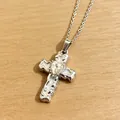 Detaillierte Makroansicht einer silbernen gotischen Kreuzkette mit einem herzförmigen Stein - Ankerkette Halskette / Weiß
